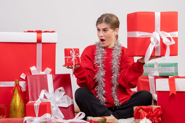 pretty female sitting around christmas presents on white