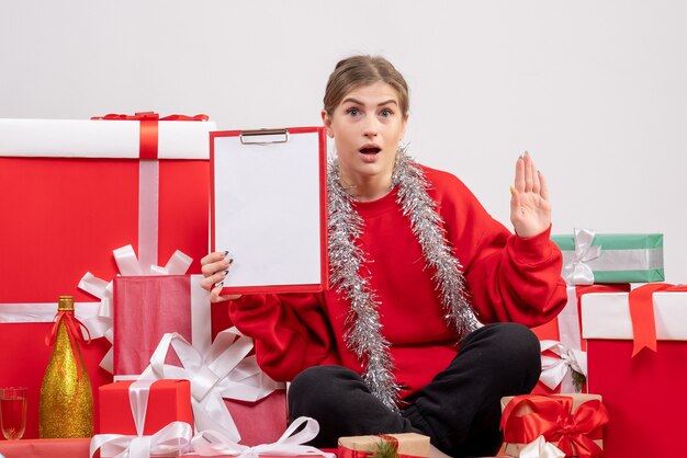 pretty female sitting around christmas presents on white