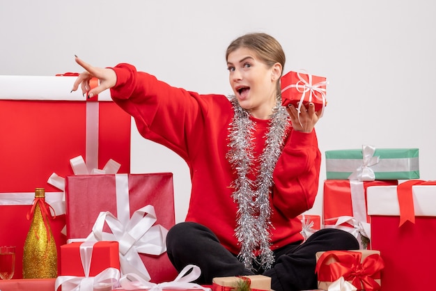 pretty female sitting around christmas presents on white