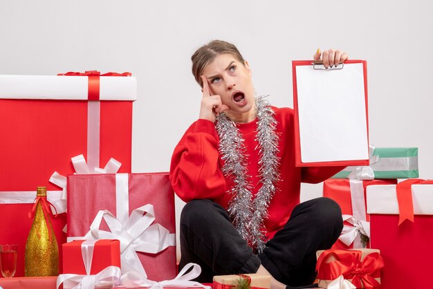 pretty female sitting around christmas presents with note on white