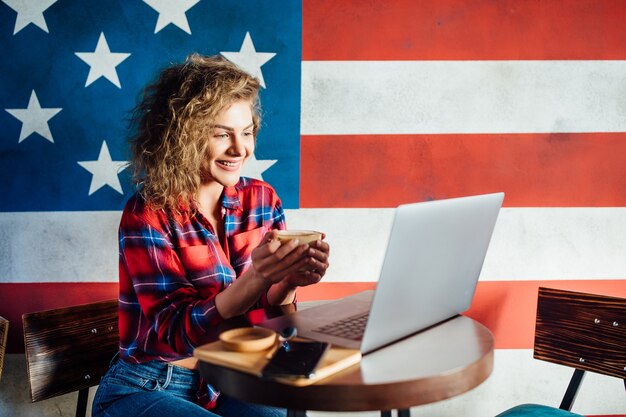 Foto gratuita bella studentessa con un sorriso carino che digita qualcosa sul net-book mentre si rilassa dopo le lezioni all'università