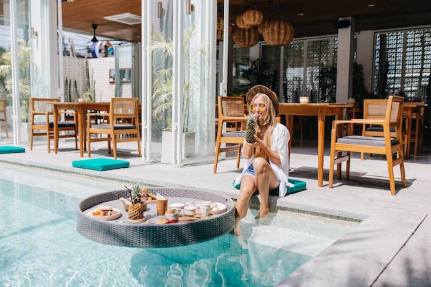 Pretty female tourist drinking cocktail in resort cafe in morning.