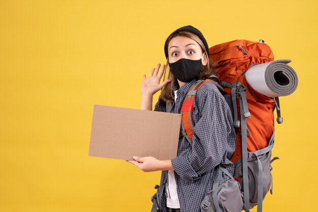 黒いマスクと段ボールを保持しているバックパックを持つかなりの女性旅行者