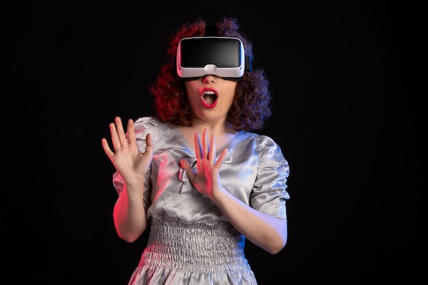 Pretty female wearing virtual reality headset on dark surface