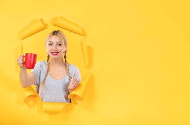 黄色い紙の背景のショッピング広告にお茶のカップときれいな女性