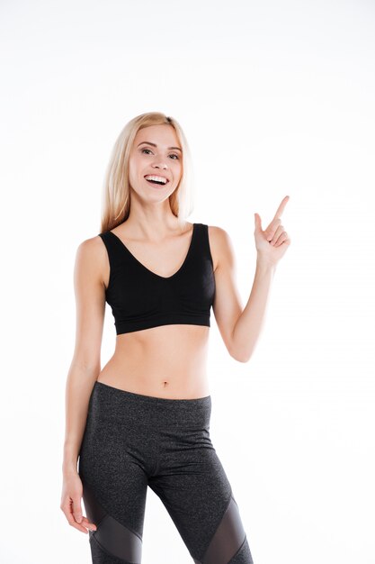 Pretty fitness woman pointing to copyspace