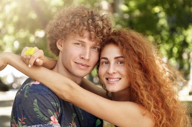 Foto gratuita donna abbastanza lentigginosa con un sorriso gentile che abbraccia il suo bel ragazzo