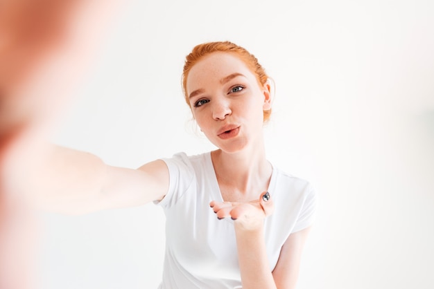 Pretty ginger woman making selfie and sends air kiss