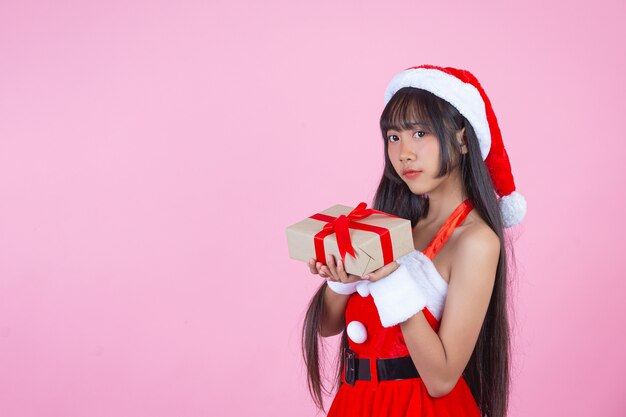 クリスマスの贈り物を保持しているクリスマスの衣装でかわいい女の子