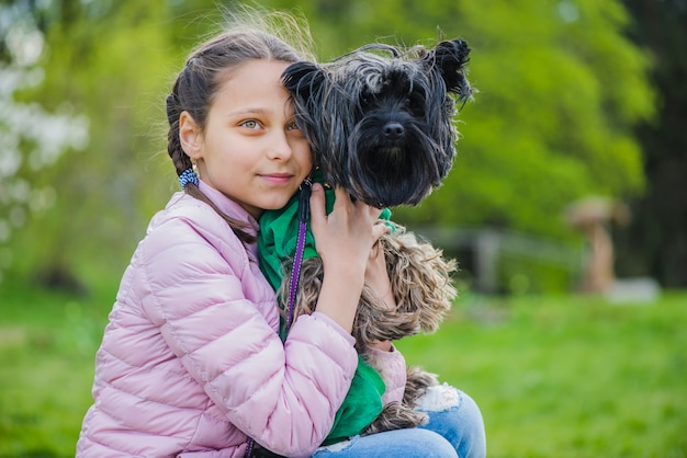 Pretty girl embracing her dog outdoors