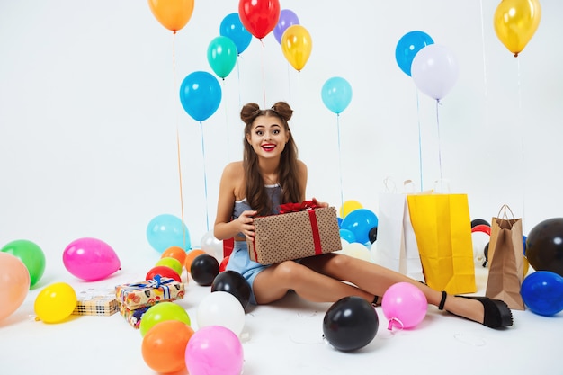 Pretty girl in fancy dress looks surprised holding present box