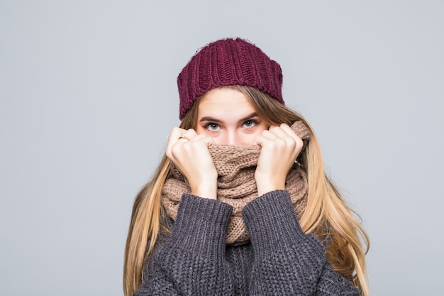 Красивая девушка в сером свитере и шарфе холодна на сером