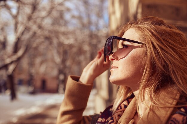 Pretty girl is looking on the sun via sunglasses