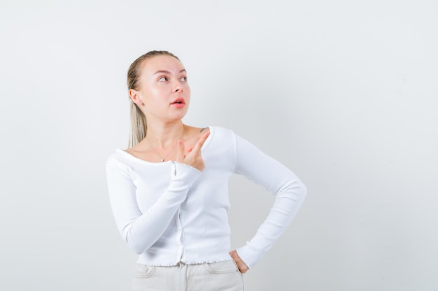 Pretty girl is showing something at right side on white background