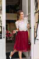 Free photo pretty girl in marsala tulle skirt on street. she holds flowers and smiling to side