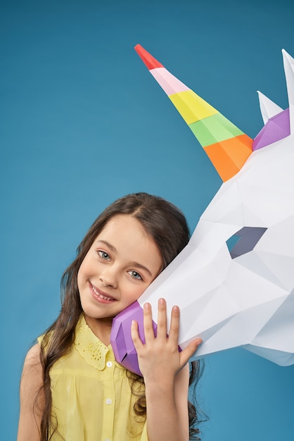 Pretty girl playing with paper unicorn and laughing