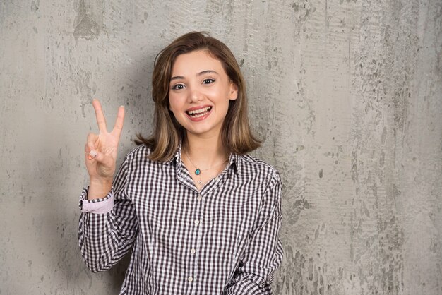 A pretty girl showing two fingers victory sign.