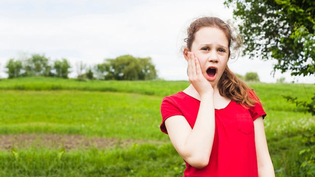 Free photo pretty girl standing in park having toothache