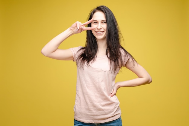 Bella ragazza in cima bianca con segno di pace