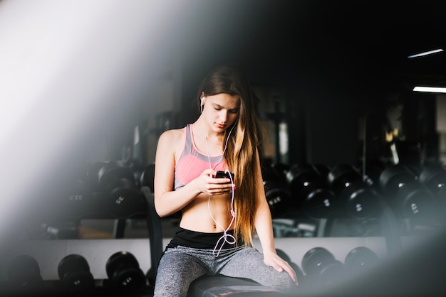 Pretty girl with headphones in gym