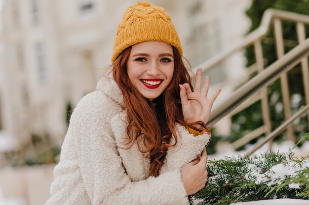 Pretty girl with long dark hair laughing in winter. Outdoor shot of romantic caucasian woman chilling in cold day.