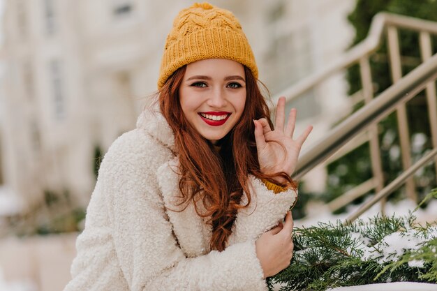 Pretty girl with long dark hair laughing in winter. Outdoor shot of romantic caucasian woman chilling in cold day.
