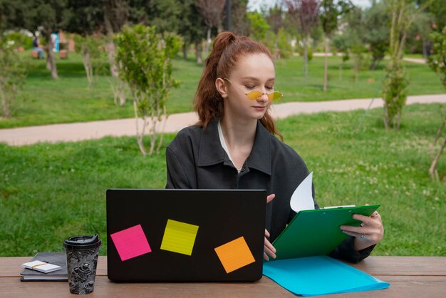 Pretty girl with red hair sitting looking down opening folder