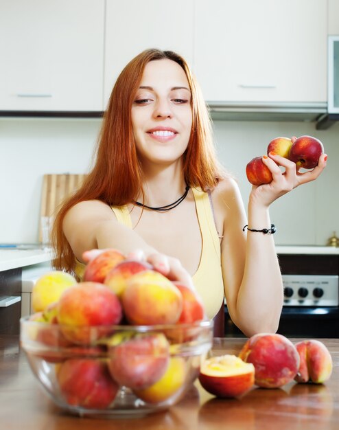 Bella ragazza in giallo mangia pesche