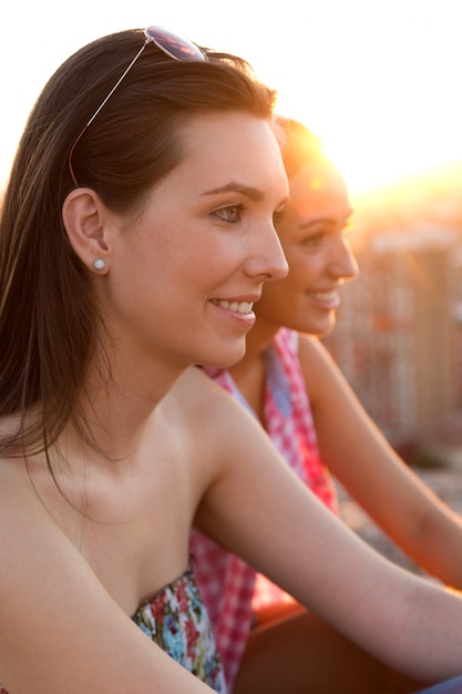 Foto gratuita ragazze graziose che si siedono sul tetto al tramonto.