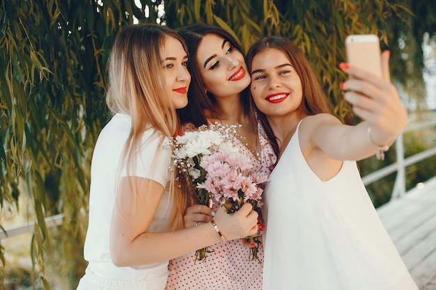 Free photo pretty girls in a summer park with a phone