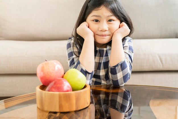 新鮮なリンゴの健康食品のアイデアの概念を持つアジアの女の子の子供を笑顔でかなり幸せ