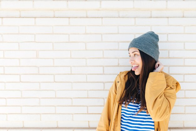 Pretty happy woman sticking her tongue out in front of brick wall