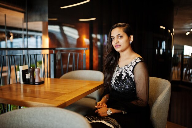 Pretty indian girl in black saree dress posed at restaurant