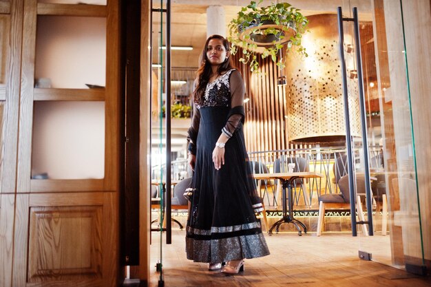 Pretty indian girl in black saree dress posed at restaurant