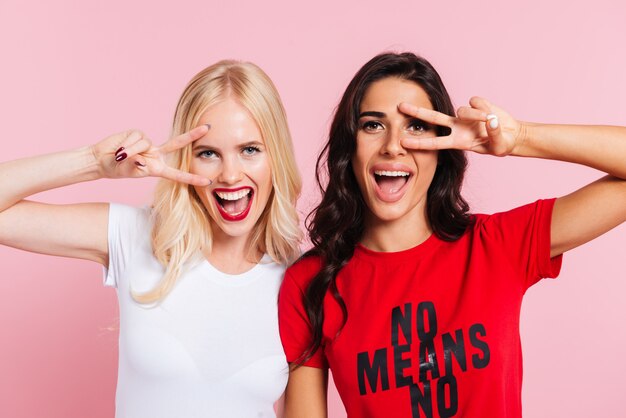 Pretty ladies showing peace gesture and smiling isolated