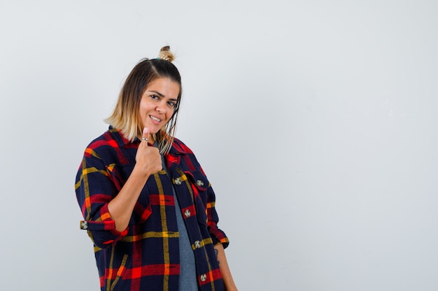 Free photo pretty lady in casual shirt showing thumb up and looking satisfied , front view.