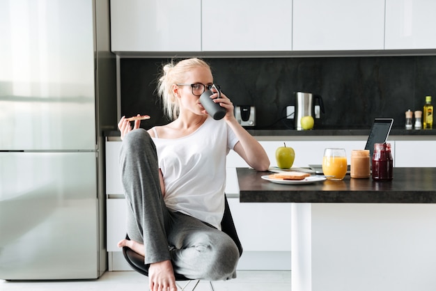 Pretty lady drinking tea and eating bread with jam in the morning