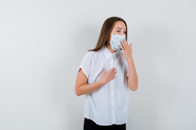 Pretty lady holding hand on chest and near mask