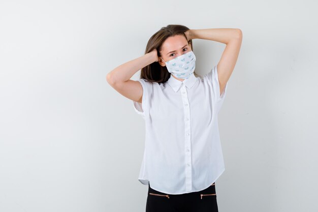 Pretty lady holding hands on head while wearing mask