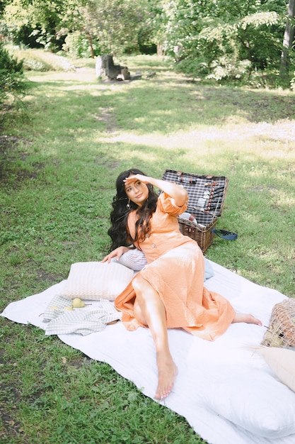 Pretty lady in orange dress lying and looking above in nature during daytime .