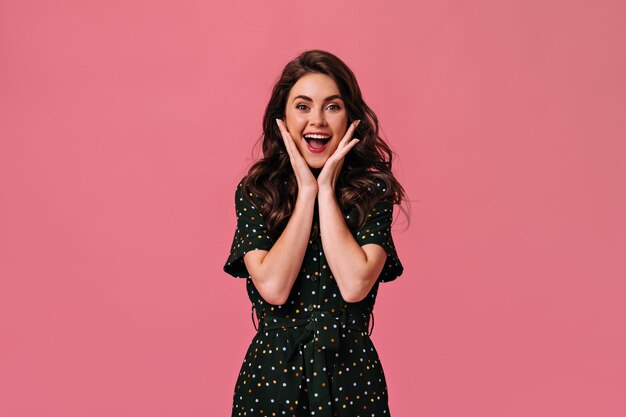 Pretty lady in polka dot outfit smiling on pink wall