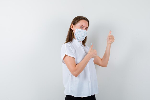 Pretty lady showing thumbs up while wearing mask