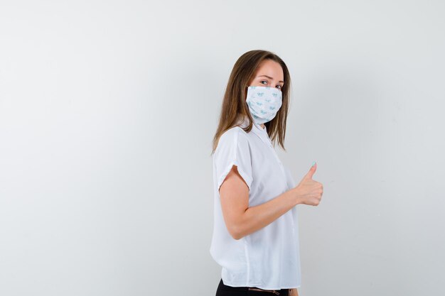 Pretty lady showing thumbs up while wearing mask