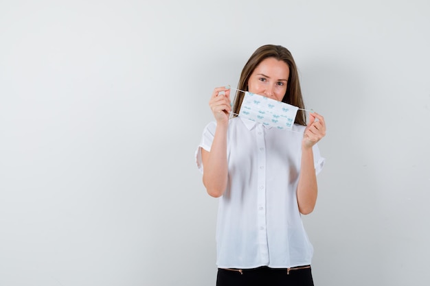 Pretty lady in t-shirt holding mask