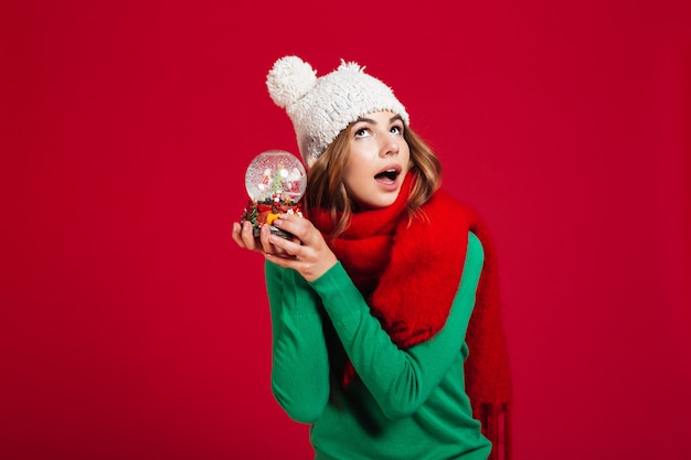 Pretty lady wearing hat and warm scarf holding christmas toy