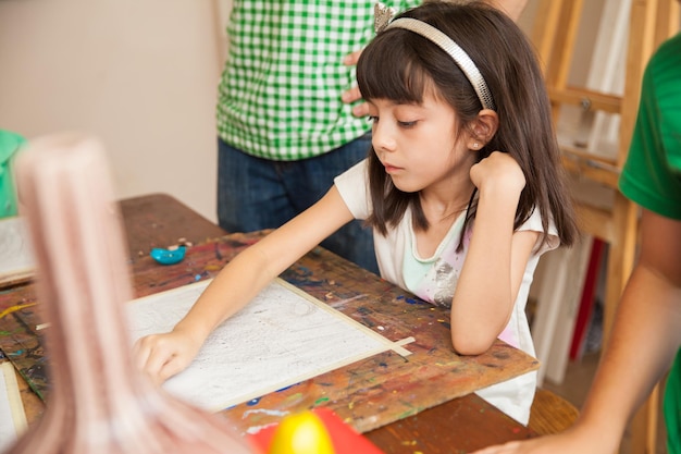 Pretty little girl drawing with a pencil and copying a model during art class