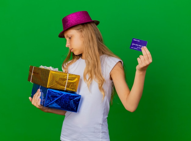 Foto gratuita bambina graziosa in cappello di festa che tiene i contenitori di regalo