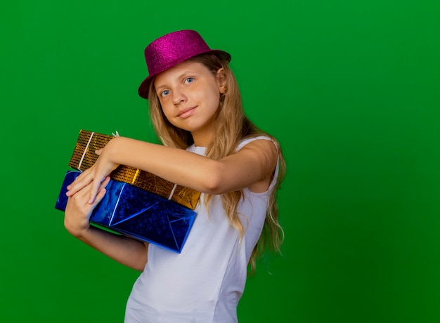 Pretty little girl in holiday hat holding gift boxes