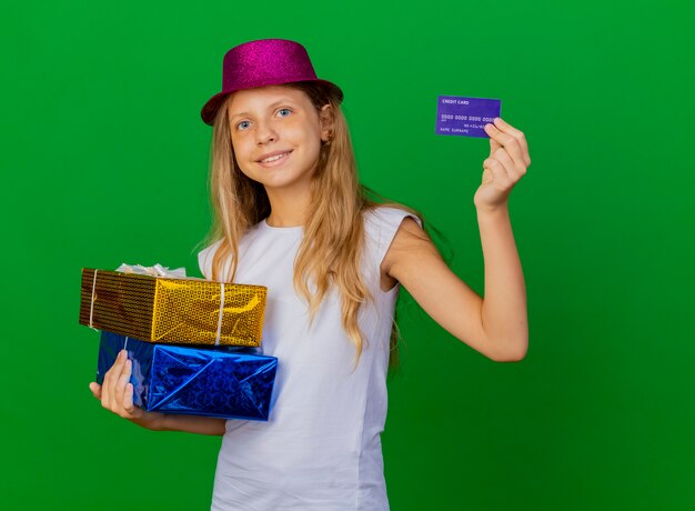 Pretty little girl in holiday hat holding gift boxes