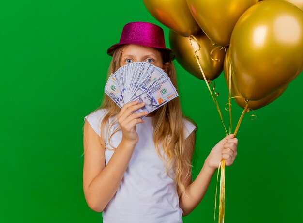 Pretty little girl in holiday hat holding money